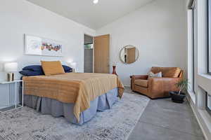 Bedroom featuring vaulted ceiling and concrete floors
