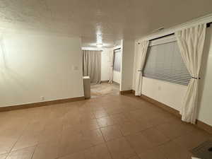 Spare room featuring baseboards, a textured ceiling, and visible vents