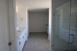 Bathroom with baseboards, double vanity, tile patterned floors, and a stall shower