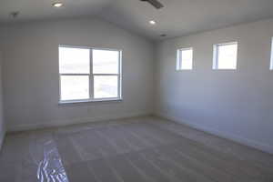 Empty room featuring carpet flooring, lofted ceiling, visible vents, and a healthy amount of sunlight