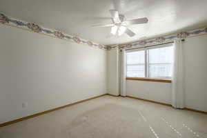 Unfurnished room featuring light colored carpet, a textured ceiling, baseboards, visible vents, and ceiling fan