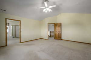 Unfurnished bedroom featuring carpet floors, baseboards, lofted ceiling, and visible vents