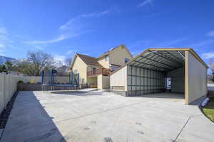 View of patio / terrace featuring a trampoline, driveway, a carport, and fence