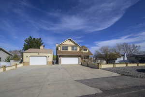 View of front of home featuring a chimney, fence, and concrete driveway