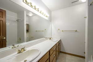 Bathroom with double vanity, a sink, baseboards, and visible vents