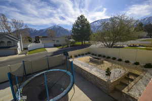 View of patio with a fenced backyard, a garden, a mountain view, and a trampoline
