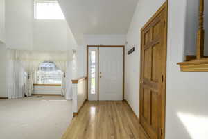 Entryway featuring baseboards, light wood-style flooring, and light colored carpet