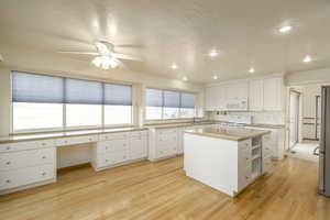 Kitchen featuring white appliances, ceiling fan, white cabinetry, a sink, and light wood-style floors