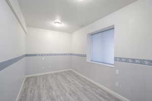 Spare room with wood finished floors, a wainscoted wall, baseboards, and visible vents