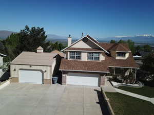View of front of property featuring a mountain view, a chimney, roof with shingles, and brick siding