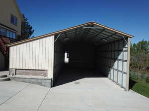 View of outdoor structure with concrete driveway and a carport