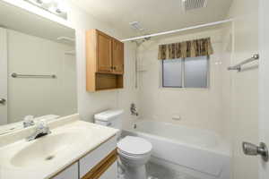 Bathroom featuring visible vents, toilet, vanity, and washtub / shower combination