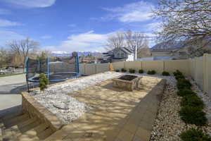 View of patio / terrace with a trampoline, a fenced backyard, an outdoor fire pit, and a mountain view