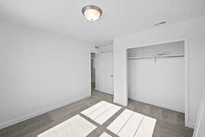 Unfurnished bedroom featuring baseboards, visible vents, a closet, and carpet floors