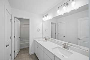 Bathroom with double vanity, a sink, and toilet