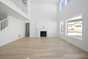 Unfurnished living room with a fireplace, baseboards, light wood finished floors, and visible vents