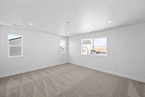 Unfurnished room with a textured ceiling, baseboards, light colored carpet, and recessed lighting