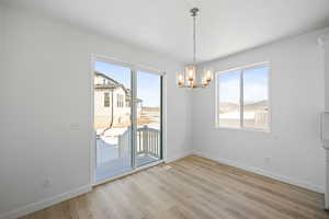 Unfurnished dining area featuring an inviting chandelier, light wood-style flooring, and baseboards