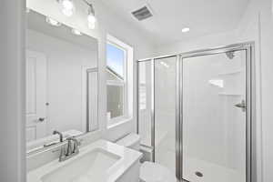 Full bath featuring toilet, vanity, a shower stall, and visible vents