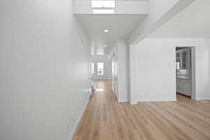 Hallway with baseboards, light wood-style flooring, and recessed lighting