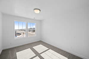 Carpeted spare room with baseboards