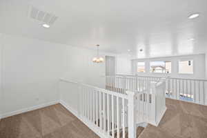 Hallway with visible vents, an upstairs landing, carpet floors, and recessed lighting