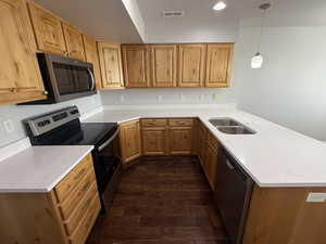Kitchen featuring a peninsula, a sink, dark wood-style flooring, visible vents, and appliances with stainless steel finishes