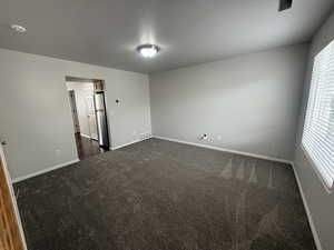 Unfurnished room featuring baseboards, dark carpet, a textured ceiling, and visible vents