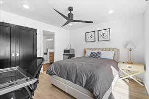 Bedroom with recessed lighting, light wood-type flooring, baseboards, ceiling fan, and ensuite bathroom