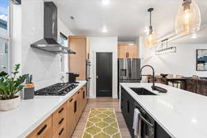 Kitchen with a sink, light wood finished floors, light brown cabinets, black appliances, and ventilation hood