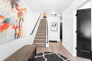 Foyer featuring baseboards, stairway, and wood finished floors