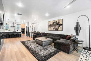 Living room with light wood-type flooring, visible vents, and recessed lighting
