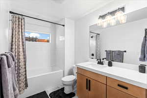 Bathroom featuring shower / bath combination with curtain, toilet, vanity, and tile patterned floors