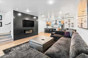 Living area featuring light wood finished floors, baseboards, a large fireplace, and stairway