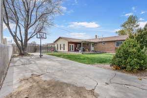 Rear view of house with a patio, a chimney, a yard, brick siding, and fence private yard
