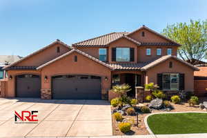 Mediterranean / spanish home with stucco siding, a tiled roof, stone siding, and concrete driveway