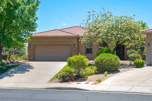 View of front facade featuring stucco siding, a tiled roof, a garage, and concrete driveway