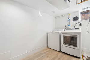 Clothes washing area with baseboards, independent washer and dryer, laundry area, and light wood finished floors