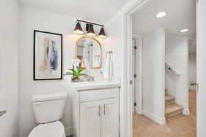 Bathroom with toilet, vanity, baseboards, and recessed lighting