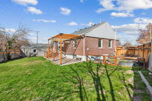 Rear view of house with a patio, a yard, a fenced backyard, brick siding, and a pergola