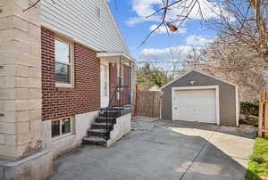 View of home's exterior with an outdoor structure, concrete driveway, fence, brick siding, and a garage