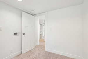 Unfurnished bedroom with baseboards, visible vents, and light colored carpet