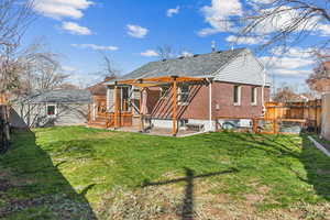 Back of property with a fenced backyard, brick siding, a yard, and a patio