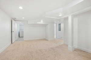 Finished below grade area with baseboards, visible vents, electric panel, and light carpet