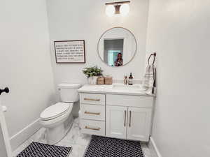 Bathroom featuring baseboards, marble finish floor, toilet, and vanity