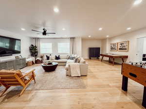 Living area with light wood-style floors, ceiling fan, and recessed lighting