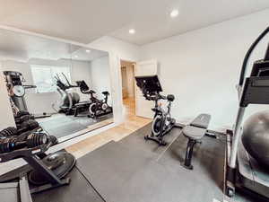 Exercise area with baseboards, light wood finished floors, and recessed lighting