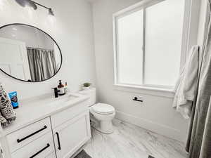 Bathroom featuring baseboards, marble finish floor, toilet, vanity, and a shower with curtain