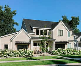 View of front of home with roof with shingles, a standing seam roof, metal roof, and a front yard