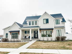 Modern farmhouse style home featuring metal roof, a standing seam roof, a front lawn, and a porch